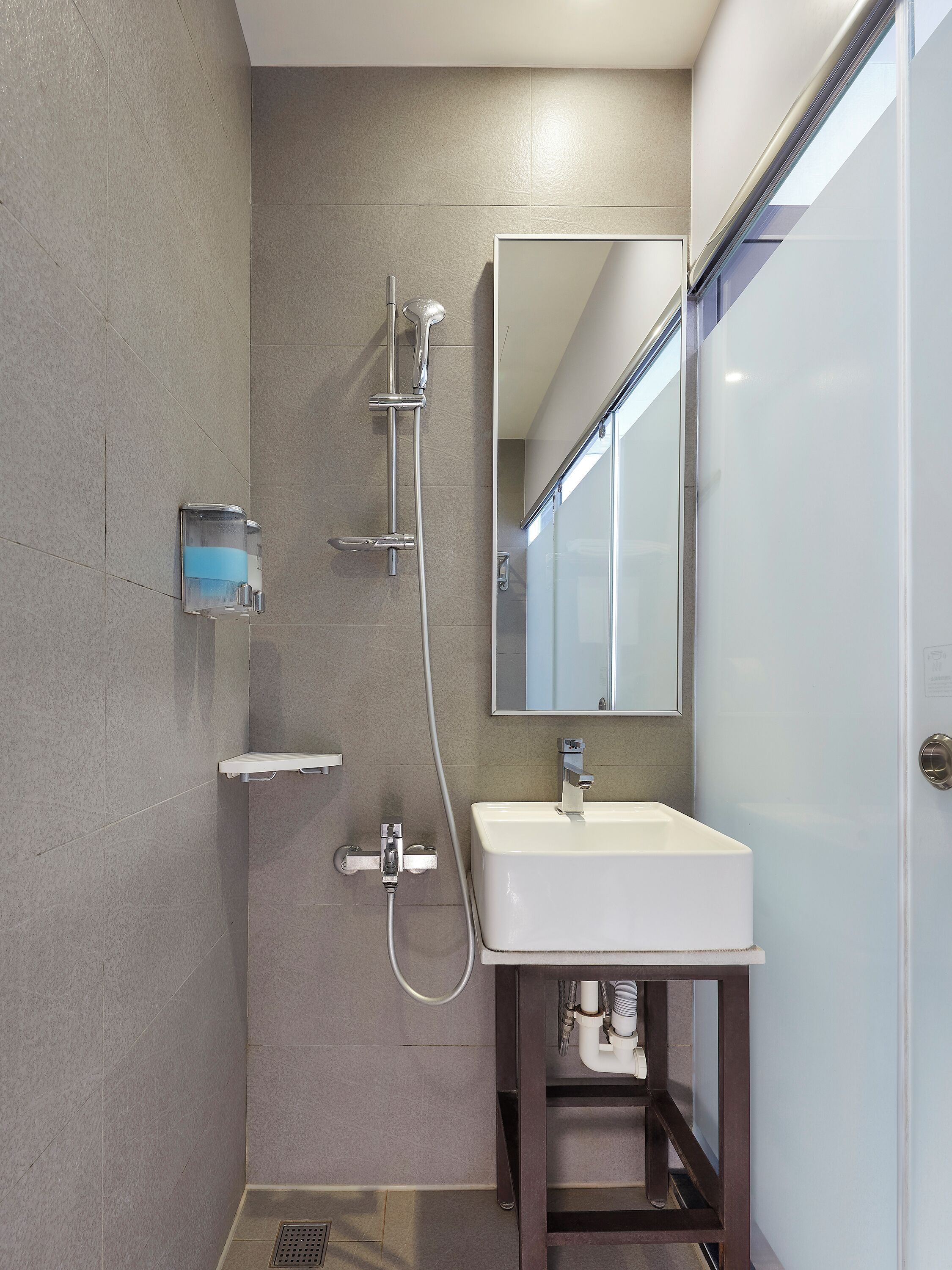 A modern bathroom with a shower, a sink, and a mirror.