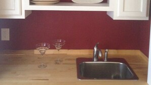 A kitchen with a wooden countertop, a stainless steel sink, and a red backsplash. - BLOSSOM VIEW COTTAGES: Luxurious 3 Bedroom + Den  Near Theaters, Downtown (Ashland)
