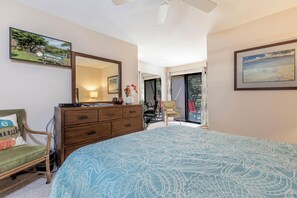 A bedroom with a large bed, a dresser, a chair, a mirror, and a door leading to a balcony.