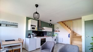 Un espacio habitable compacto con kitchenette, comedor y escalera.