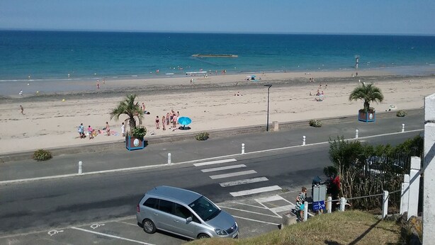 Una playa con vista despejada al mar, un área de estacionamiento y un paso de peatones.