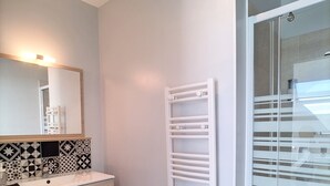 Un baño con toallero blanco, espejo y salpicadero de azulejos.