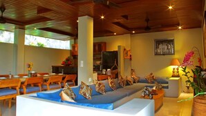 A spacious indoor area with a long dining table, multiple chairs, a sofa with patterned cushions, and a ceiling fan. - Bali style villa 5 minutes from ubud center! (Ubud)