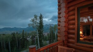A wooden cabin with a balcony overlooking a mountainous landscape.