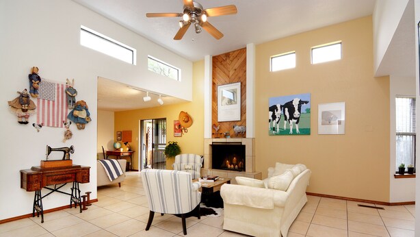 A spacious living room with a fireplace, a ceiling fan, and a large window. - Walking trails nearby, Spacious, light filled, well stocked  (Santa Fe)
