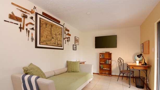 A living room with a sofa, a coffee table, a bookshelf, and a TV.