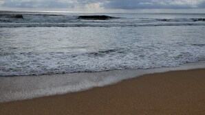 Una playa con olas y un cielo nublado.