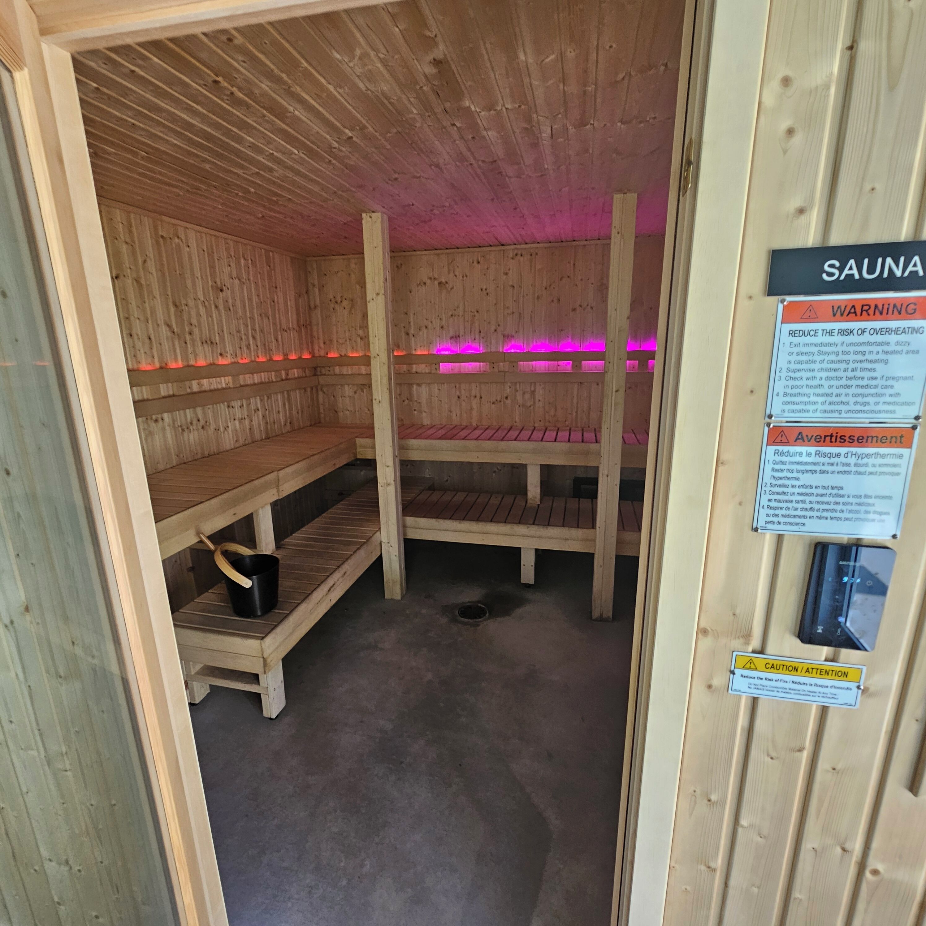 A sauna with wooden benches and a sign listing safety warnings.