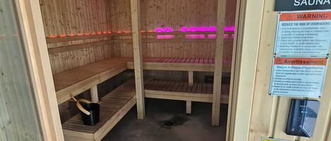 A sauna with wooden benches and a sign listing safety warnings.