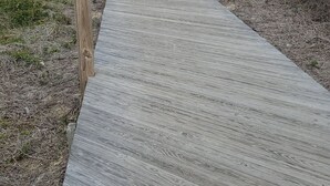 Una pasarela de madera que conduce a una cabaña en la playa con techo inclinado.