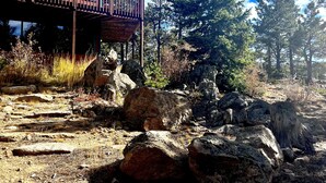 A modern building with large windows and a wooden deck, surrounded by rocky terrain and pine trees. - Stunning Views Of The Indian Peaks On Mountain Lake (Ward)