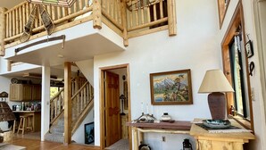 A spacious living area with a wooden staircase, a dining area, and a kitchen visible in the background. - Stunning Views Of The Indian Peaks On Mountain Lake (Ward)