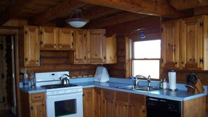 Une cuisine dotée de meubles en bois, d’une cuisinière blanche, d’un lave-vaisselle et d’une fenêtre laissant entrer la lumière naturelle.