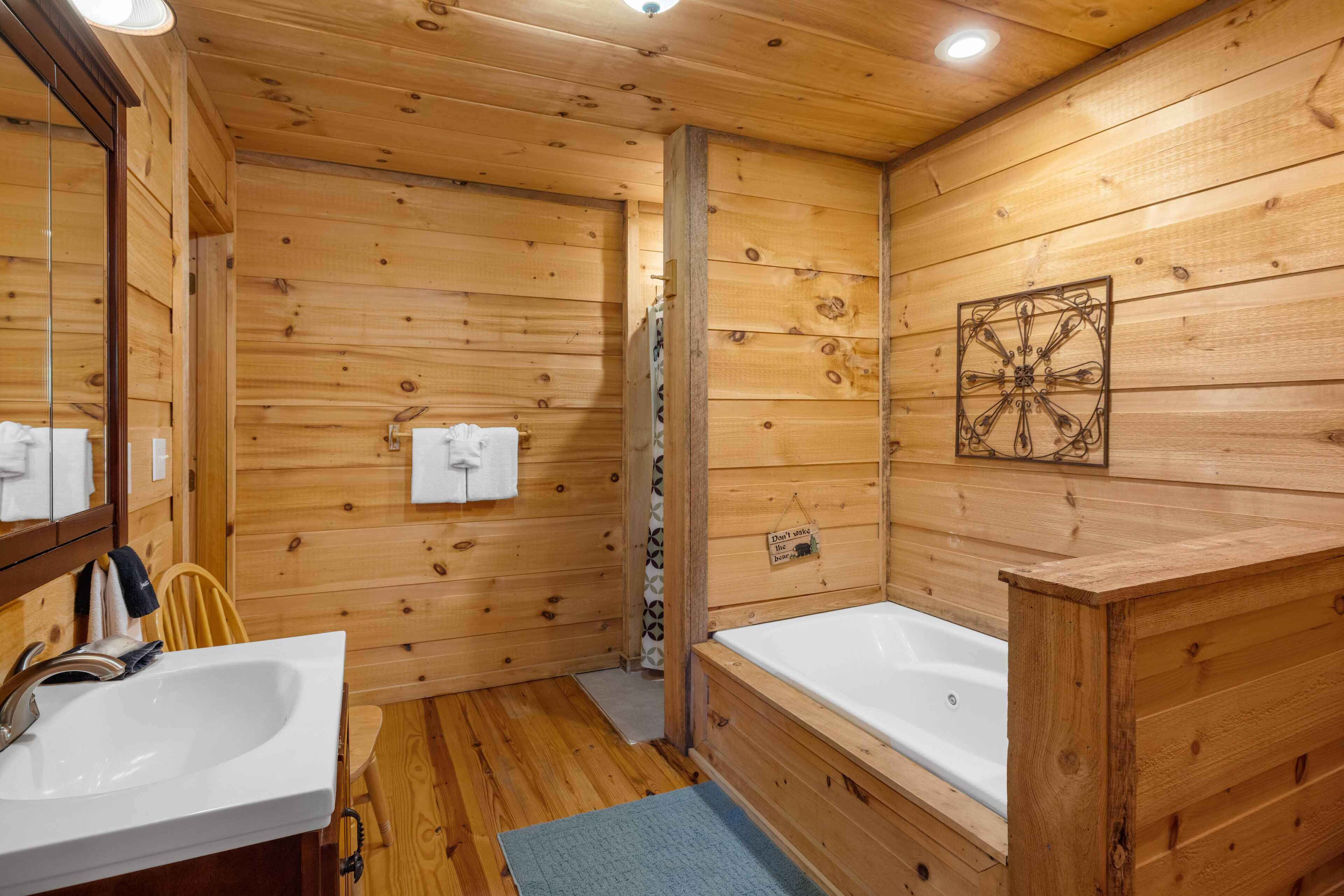 Baño de cabaña de madera con lavamanos, dos tinas y un espejo.