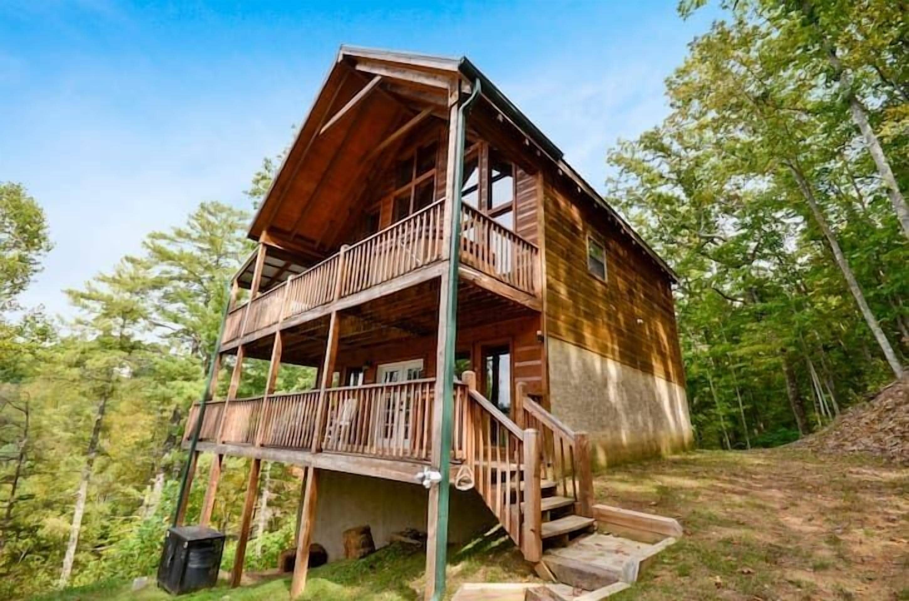 A wooden cabin with a balcony, set in a forested area.
