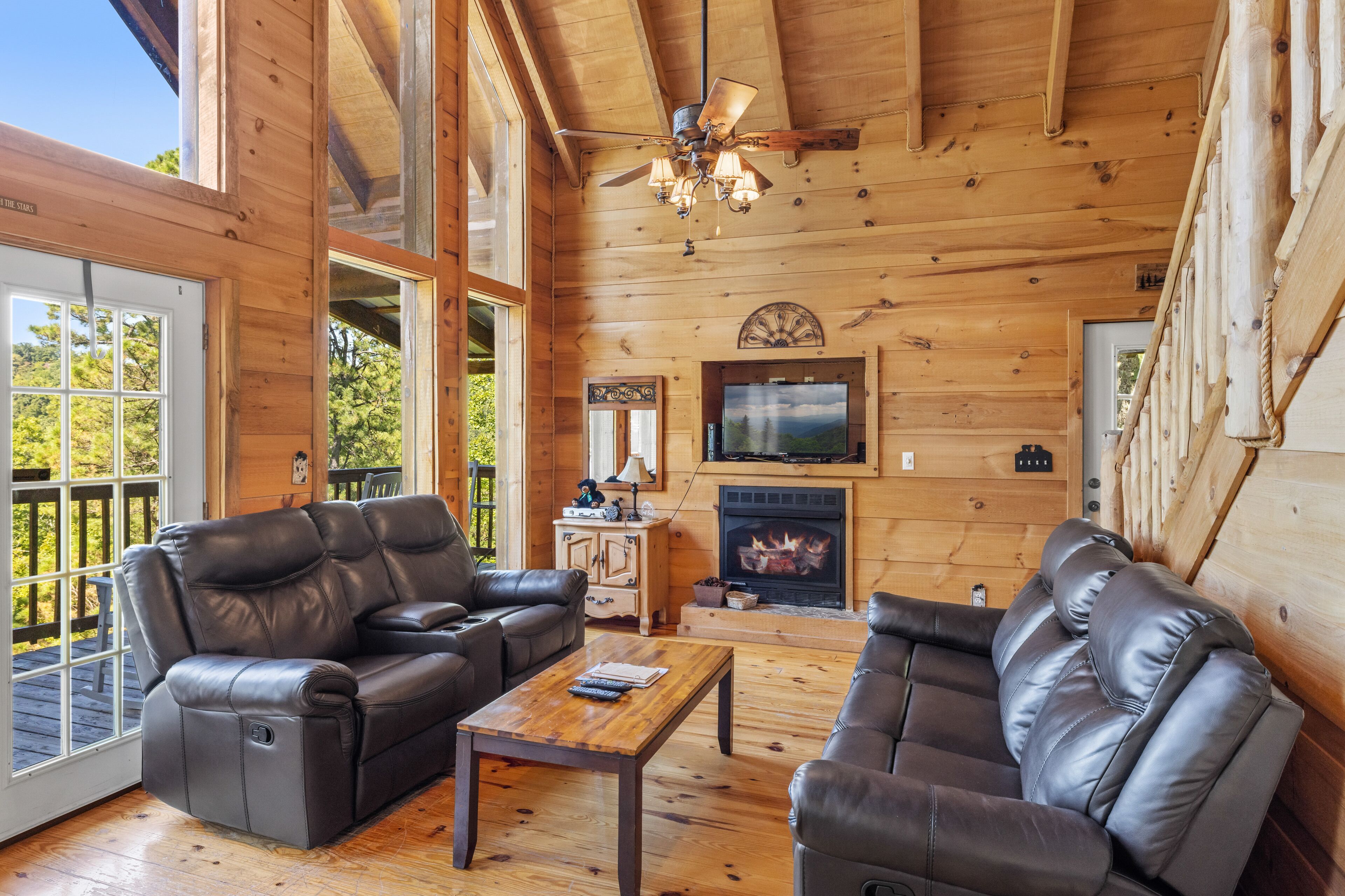 L'intérieur d'un chalet en bois, avec des canapés en cuir, une cheminée et un téléviseur.