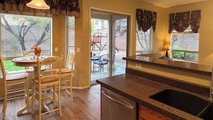 A kitchen with a built-in dishwasher, a dining area with a table and chairs, and a view of the backyard through the sliding glass door. - Furnished, 31 day min. gated cul de sac
Las Sendas amenities incl., 3 car garage (Mesa)