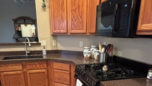 A kitchen with wooden cabinets, a black stove, a microwave, and a sink. - Furnished, 31 day min. gated cul de sac
Las Sendas amenities incl., 3 car garage (Mesa)