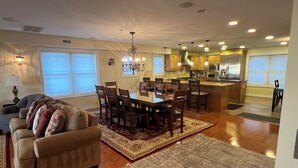 A spacious living room with a large dining table and chairs, a sofa, and a kitchen area with modern appliances. - SPACIOUS HOUSE WITH POOL OCEANVIEW 3 DECKS 4 MASTER CLOSE TO OCEAN AND BOARDWALK (Wildwood Crest)