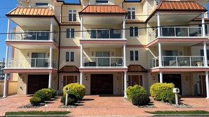 A multi-story residential building with a symmetrical facade, multiple balconies, and a central entrance with a double garage door. - SPACIOUS HOUSE WITH POOL OCEANVIEW 3 DECKS 4 MASTER CLOSE TO OCEAN AND BOARDWALK (Wildwood Crest)