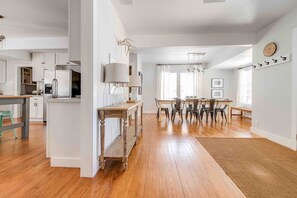 A spacious kitchen with wooden flooring, a dining area with a table and chairs, and a view of the living room.