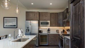 Una cocina moderna con electrodomésticos de acero inoxidable, armarios de madera y encimera de mármol.