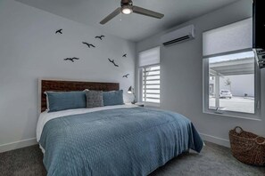 A bedroom with a bed, a ceiling fan, a window with blinds, and a wall-mounted air conditioner. - The Lofts #14 | Townhome Pool Resort | Poolside (Saint George)