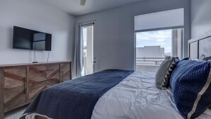 A bedroom with a bed, a television mounted on the wall, a ceiling fan, and a window with a view. - The Lofts #14 | Townhome Pool Resort | Poolside (Saint George)