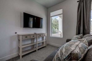 A bedroom with a bed, a TV mounted on the wall, a window, and a bedside table. - The Lofts #14 | Townhome Pool Resort | Poolside (Saint George)