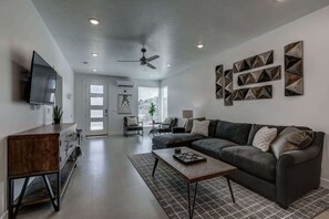 A modern living room with a sofa, coffee table, and a flat-screen TV. - The Lofts #14 | Townhome Pool Resort | Poolside (Saint George)