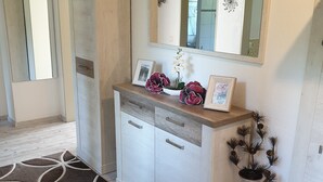 Une salle de bain moderne avec un meuble-lavabo en bois, un grand miroir et un vase décoratif.