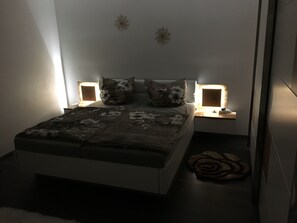 A bedroom with a bed, two bedside tables, and two wall-mounted lamps. - Family friendly accommodation (Furth im Wald)