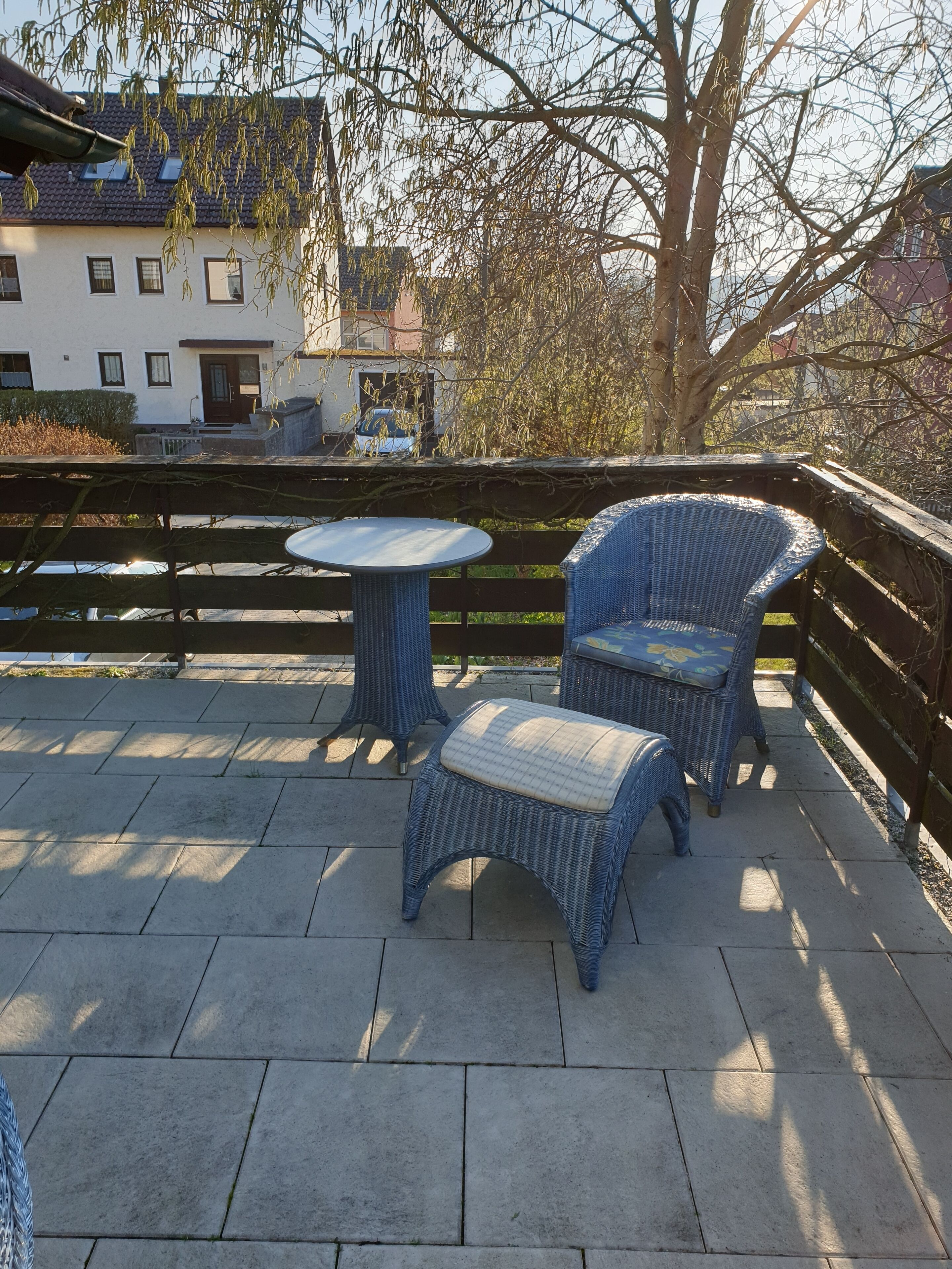 A patio with wicker furniture, a round table, and a chair.