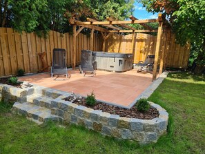 A backyard patio with a hot tub, two lawn chairs, and a wooden pergola. - Family friendly accommodation (Furth im Wald)