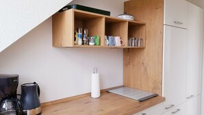 A kitchenette with a coffee maker, a paper towel dispenser, and a shelf with jars and books. - Wonderful apartment! WLAN Only 400m to the sea and the center (Osteseebad Boltenhagen)