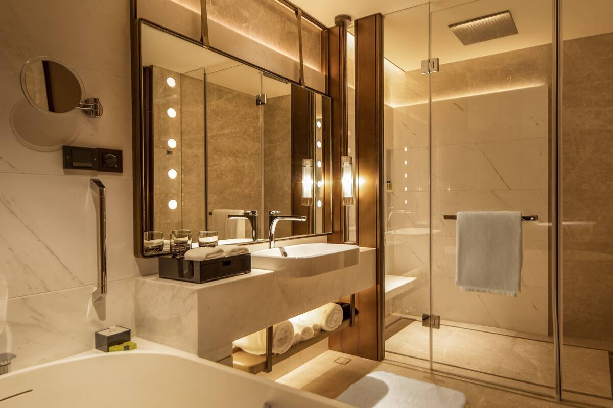 Un baño moderno con un espejo grande, tocador y ducha a ras de suelo.