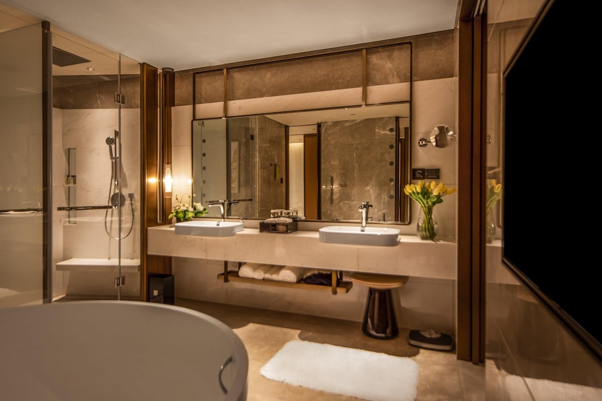 Un baño moderno con una bañera, dos lavamanos, un espejo grande y una ducha.