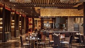 Ein modernes Restaurant mit Barbereich, Sitzgelegenheiten mit gestreiften Kissen und einer gemusterten Decke.