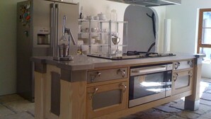 A kitchen with a built-in oven, a stainless steel range hood, and a refrigerator with magnets. - The Vandees (Craigavon)