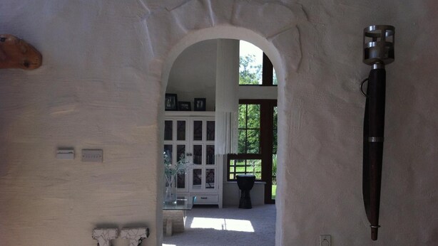 An arched doorway leading to a room with a white cabinet, a black object on the wall, and a view of the outdoors. - The Vandees (Craigavon)
