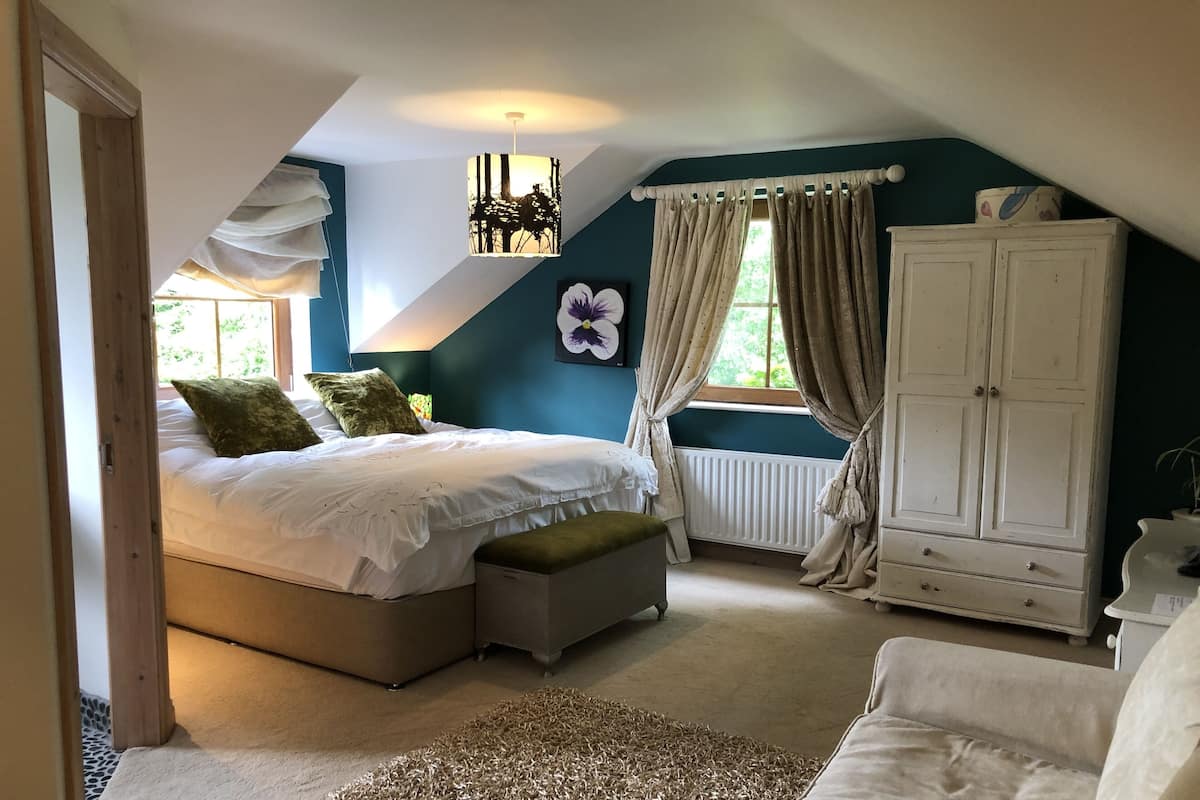 A bedroom with a bed, a nightstand, a wardrobe, and a window with curtains.