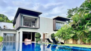 A modern two-story house with a swimming pool, outdoor seating, and lush greenery. - Baan Yamu By RESAVA (Pa Klok)