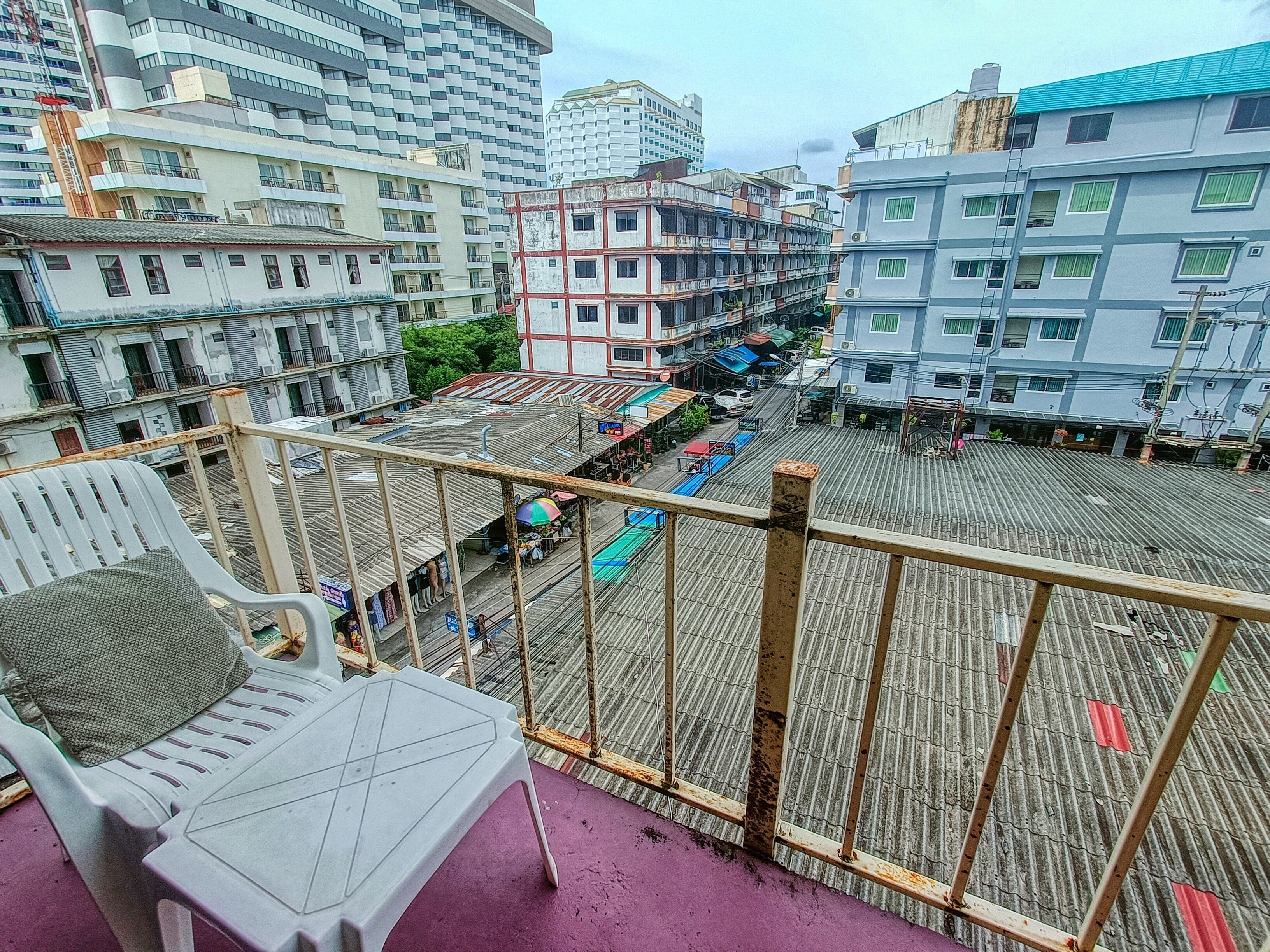 Een balkon met uitzicht op een stadsgezicht, met meerlaagse gebouwen en een markt eronder.