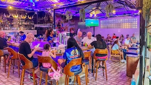 A restaurant with a bar area, tables, chairs, and a television screen. - Happy Vikings - Beachfront (Pattaya)
