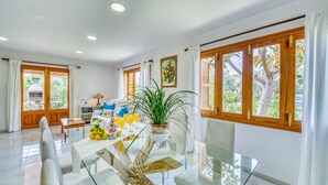 A spacious dining area with a glass table, white chairs, and a potted plant. - Finca Rosas 28 with private pool in Mallorca (Manacor)