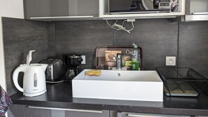 A compact kitchen with a white sink, a coffee maker, a toaster, and a microwave above the counter. - Cottage with terrace and parking. (Blois)