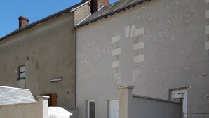 A building with a gravel driveway, potted plants, and a white door. - Cottage with terrace and parking. (Blois)