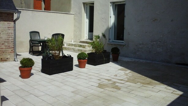 A courtyard with potted plants, a table, and chairs. - Cottage with terrace and parking. (Blois)