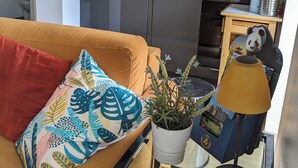 A living room with a sofa, a colorful pillow, a potted plant, a lamp, and a magazine on a coffee table. - Cottage with terrace and parking. (Blois)