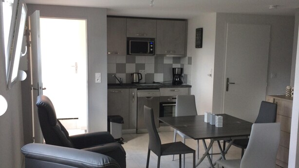 A modern kitchen with a microwave, stove, and coffee maker. There is a dining table with chairs and a sofa. - Studio, two people, Haut-Doubs, Plateau du Pays Horloger between Maîche and Mor (Le Russey)